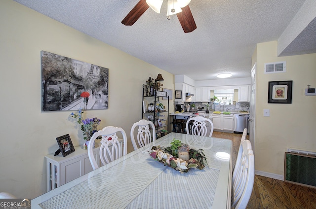 dining space featuring a textured ceiling, ceiling fan, sink, and dark wood-type flooring