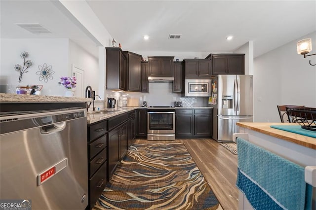 kitchen with sink, stainless steel appliances, backsplash, wood-type flooring, and dark brown cabinets