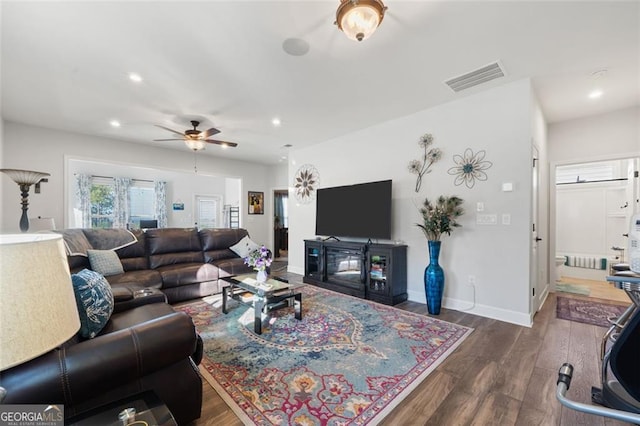 living room featuring ceiling fan and dark hardwood / wood-style flooring