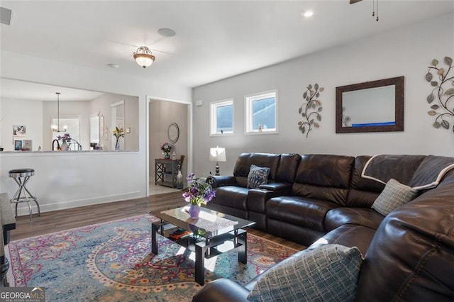 living room with ceiling fan with notable chandelier and dark hardwood / wood-style flooring