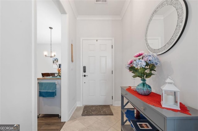 foyer featuring ornamental molding, light tile patterned floors, and an inviting chandelier