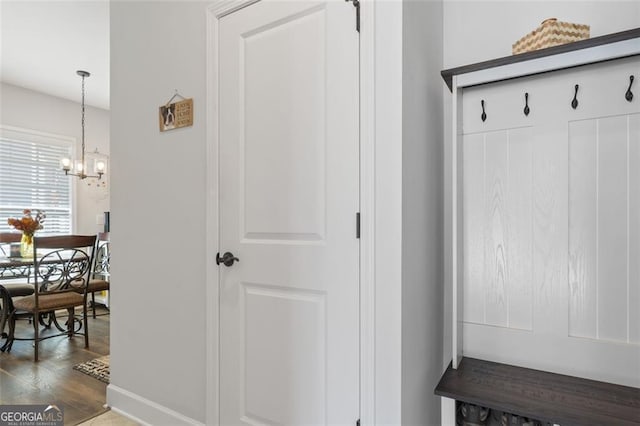 mudroom with dark wood-type flooring and an inviting chandelier