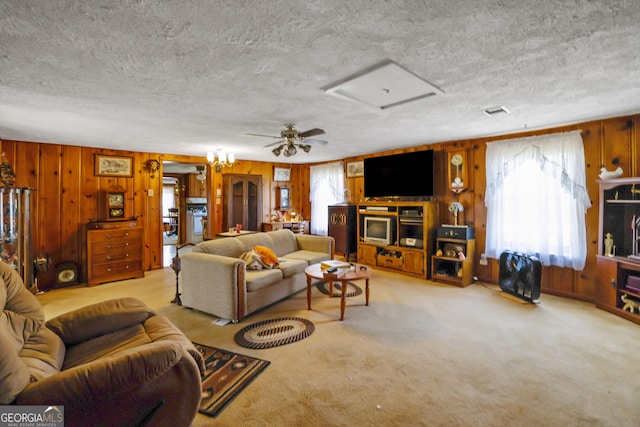 carpeted living room with a textured ceiling, ceiling fan, and wooden walls