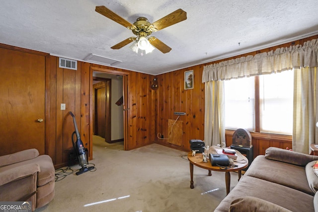 living room with wood walls, ceiling fan, and a textured ceiling