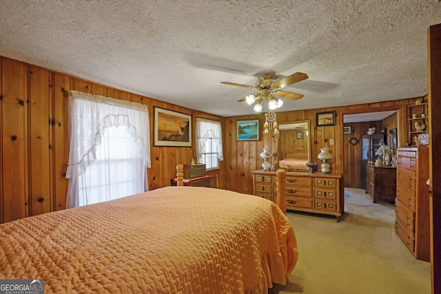 carpeted bedroom featuring wood walls, ceiling fan, and a textured ceiling