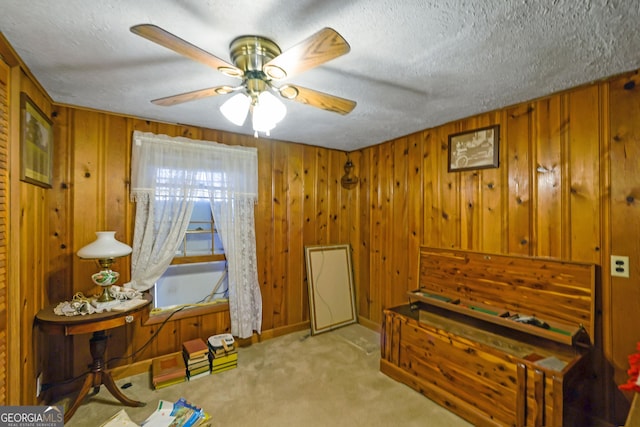 miscellaneous room with a textured ceiling, light colored carpet, ceiling fan, and wooden walls