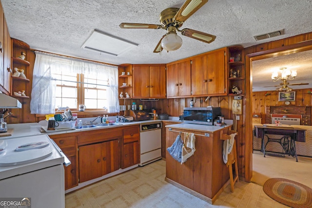 kitchen with a textured ceiling, ceiling fan, wooden walls, sink, and dishwasher