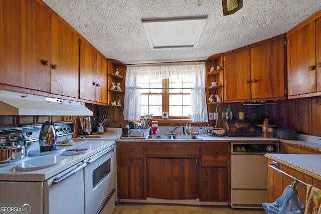 kitchen featuring a textured ceiling, wooden walls, sink, and white appliances