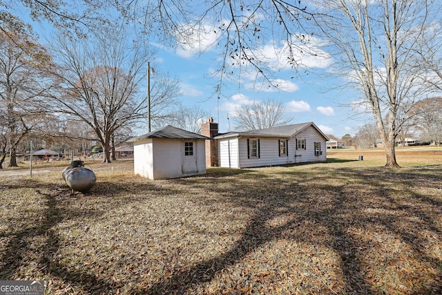 rear view of property with a lawn and an outbuilding