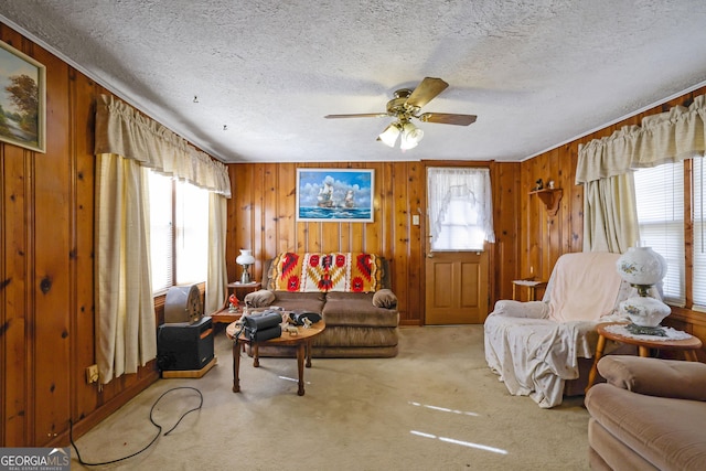 carpeted living room featuring a textured ceiling, ceiling fan, and wooden walls