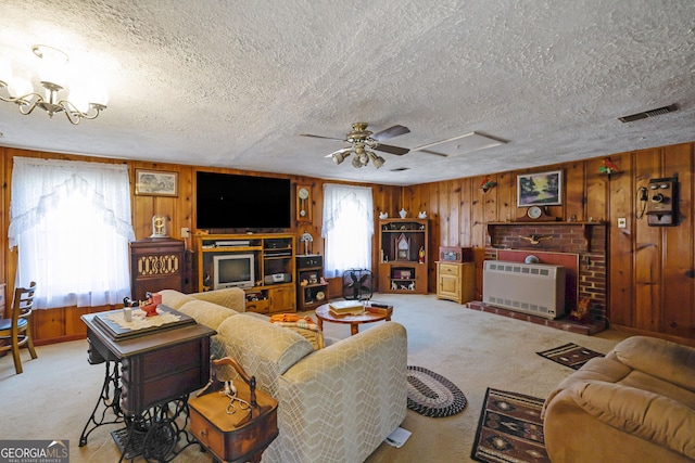 living room featuring light carpet, a textured ceiling, wooden walls, and heating unit