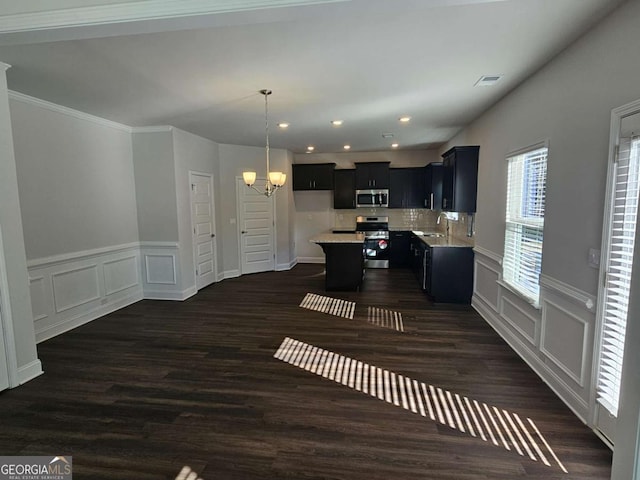 kitchen with a notable chandelier, light countertops, appliances with stainless steel finishes, a sink, and dark cabinetry