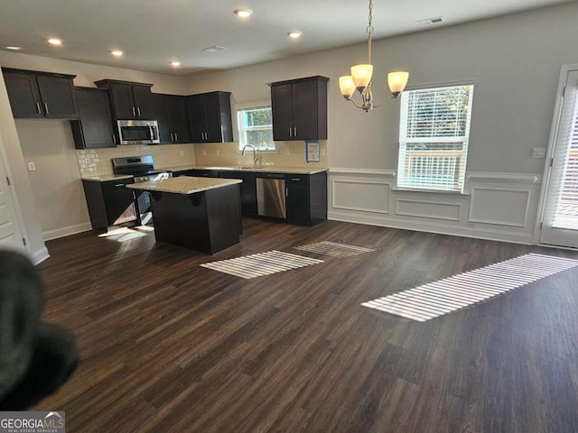 kitchen featuring a center island, dark wood finished floors, stainless steel appliances, visible vents, and backsplash