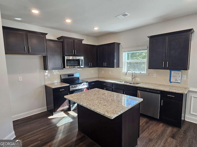 kitchen with visible vents, light stone counters, appliances with stainless steel finishes, dark wood-type flooring, and a sink