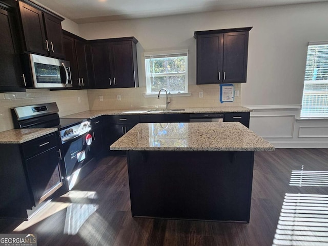 kitchen with appliances with stainless steel finishes, wainscoting, a sink, and dark wood finished floors