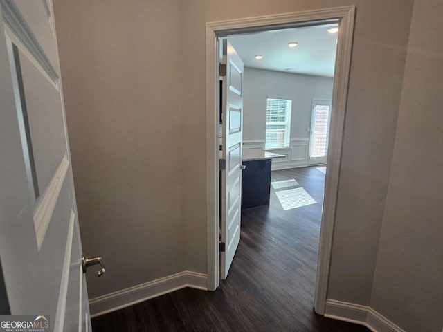 corridor featuring baseboards and dark wood finished floors