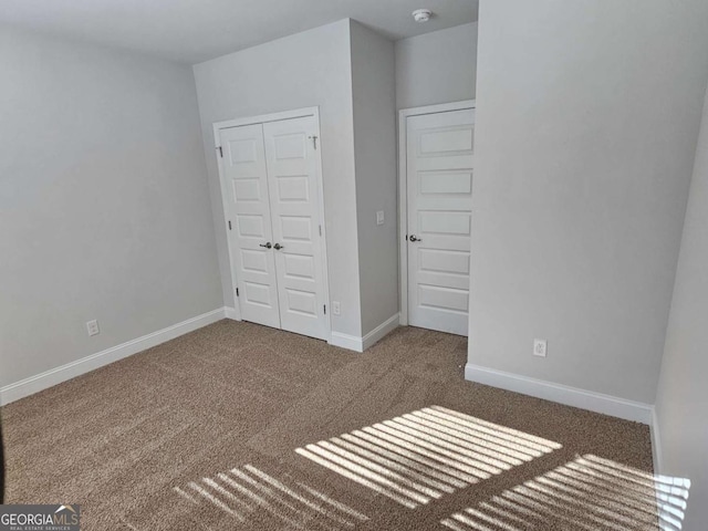 unfurnished bedroom with a closet, carpet flooring, and baseboards