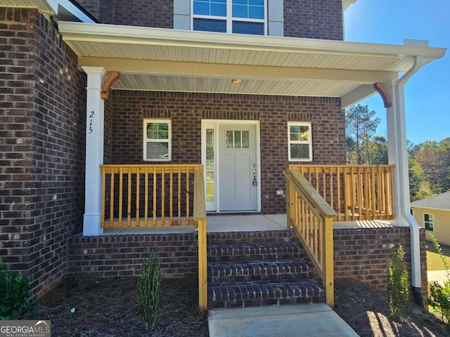 view of exterior entry with covered porch and brick siding