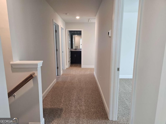 hallway with baseboards, light carpet, and an upstairs landing