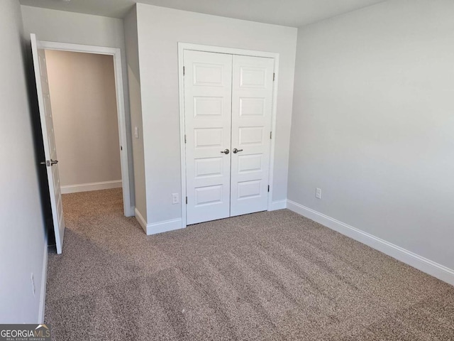 unfurnished bedroom with a closet, carpet flooring, and baseboards