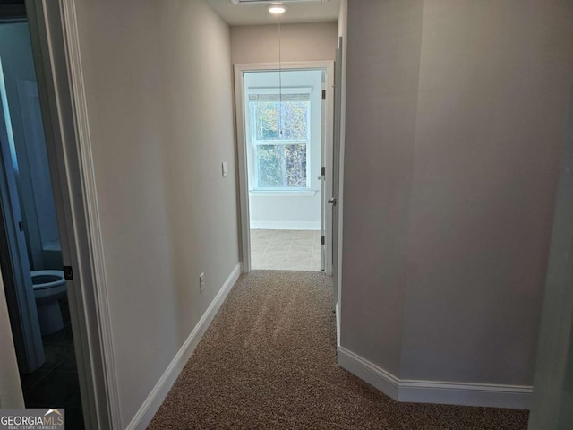 hall with attic access, carpet flooring, and baseboards