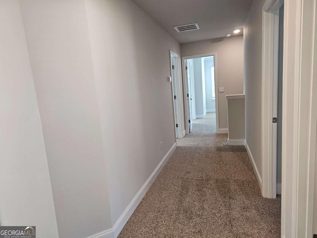 hall featuring carpet, visible vents, and baseboards