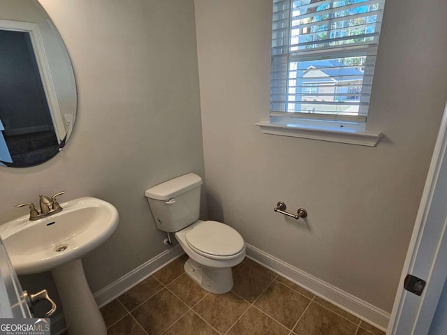 bathroom with toilet, tile patterned flooring, baseboards, and a sink