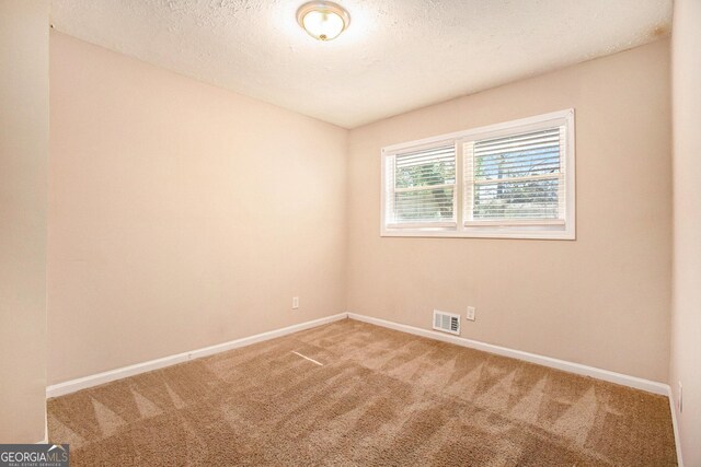 carpeted spare room with a textured ceiling