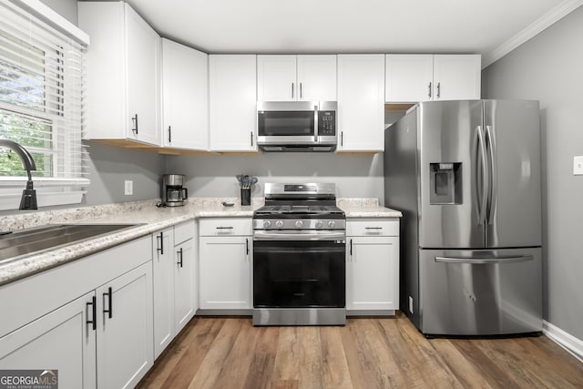 kitchen with sink, white cabinets, stainless steel appliances, and light hardwood / wood-style floors