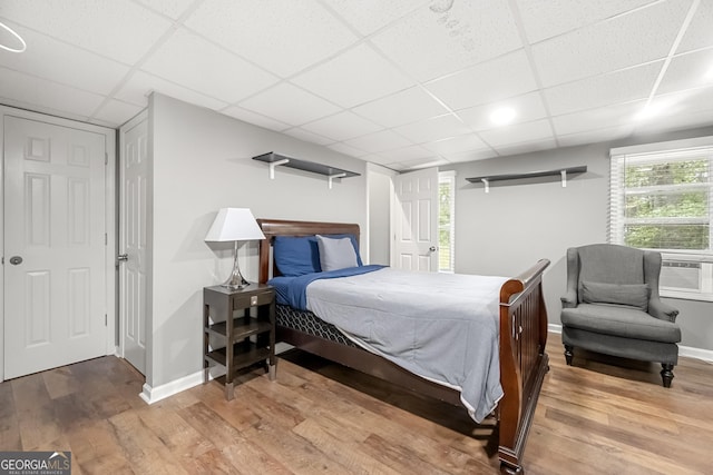 bedroom with hardwood / wood-style floors and a paneled ceiling