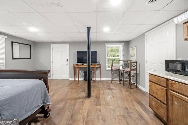 bedroom with a paneled ceiling and light hardwood / wood-style flooring