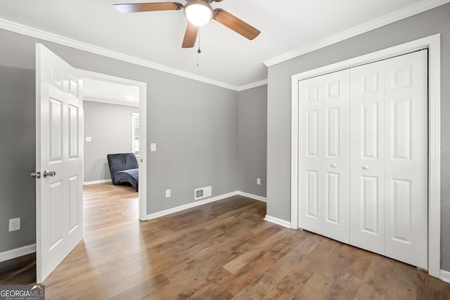 unfurnished bedroom with hardwood / wood-style floors, ceiling fan, crown molding, and a closet