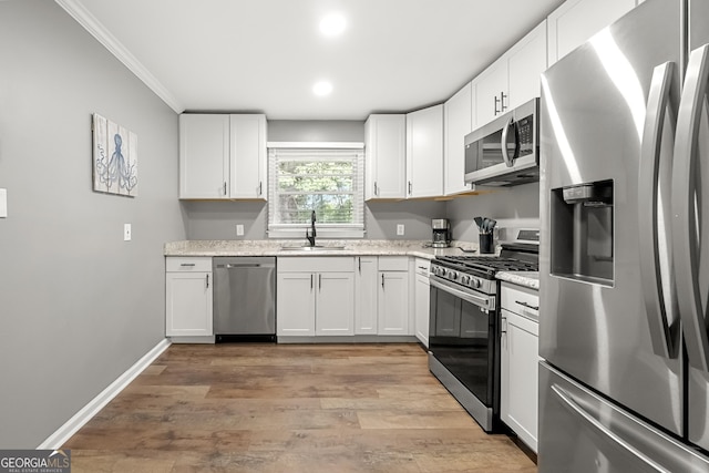 kitchen featuring white cabinets, appliances with stainless steel finishes, light wood-type flooring, and sink