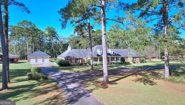 ranch-style home featuring an outbuilding, a garage, and a front lawn