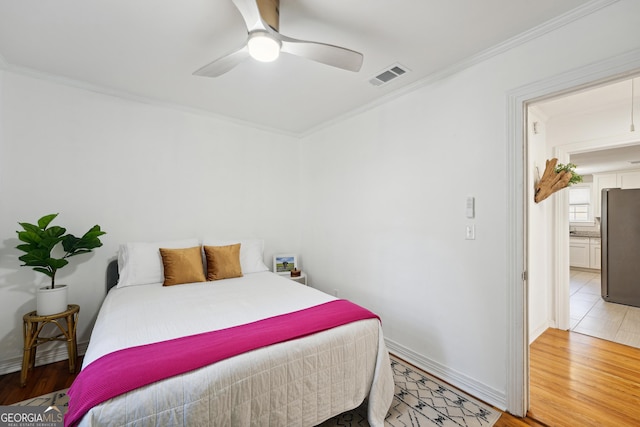 bedroom featuring wood-type flooring, stainless steel refrigerator, ceiling fan, and ornamental molding