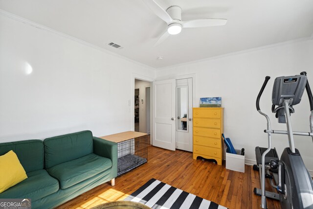 interior space with ceiling fan, wood-type flooring, and ornamental molding