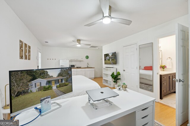 office space featuring light hardwood / wood-style floors, ceiling fan, and sink