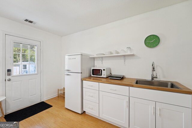 kitchen featuring white cabinets, white appliances, butcher block countertops, and sink