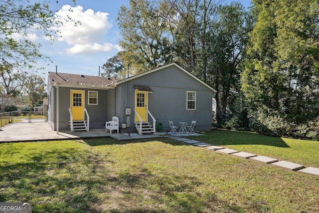 back of property with a yard and a patio