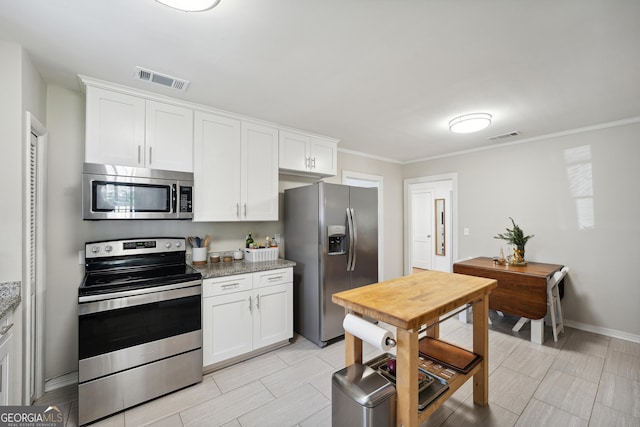 kitchen featuring light stone countertops, white cabinetry, ornamental molding, and appliances with stainless steel finishes