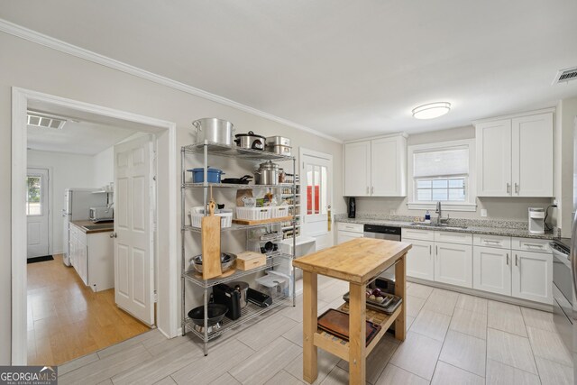 kitchen featuring plenty of natural light, light wood-type flooring, white cabinetry, and sink