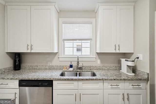 kitchen with light stone countertops, sink, white cabinets, and stainless steel dishwasher