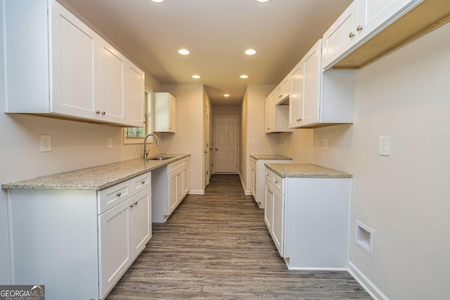 kitchen with light stone countertops, white cabinetry, a sink, and recessed lighting