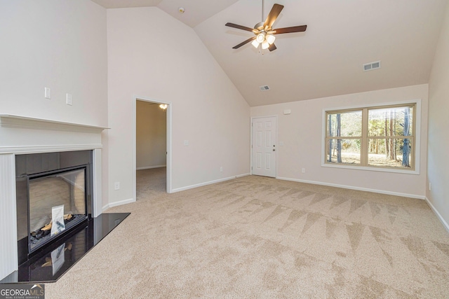 unfurnished living room featuring carpet, visible vents, a glass covered fireplace, high vaulted ceiling, and baseboards