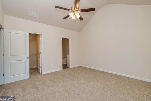 unfurnished bedroom with carpet floors, visible vents, a spacious closet, vaulted ceiling, and baseboards