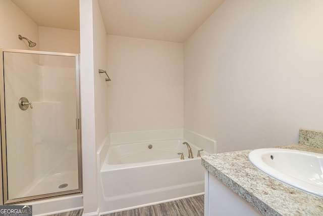 full bathroom with wood finished floors, a stall shower, vanity, and a bath