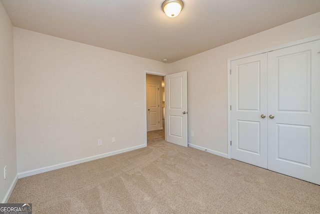 unfurnished bedroom with carpet, baseboards, and a closet