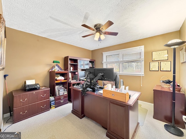 carpeted home office with ceiling fan and a textured ceiling