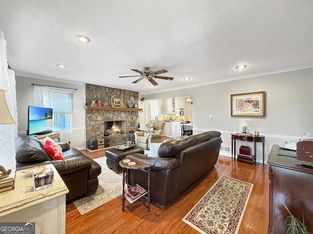 living room with a textured ceiling, wood-type flooring, and a fireplace