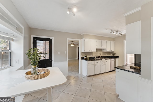 kitchen with a sink, dark countertops, white cabinetry, light tile patterned floors, and dishwasher